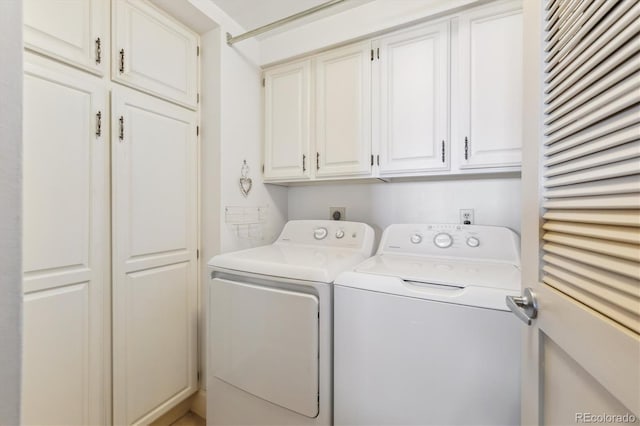 clothes washing area featuring washing machine and dryer and cabinet space