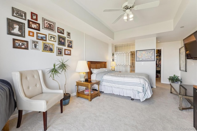 carpeted bedroom with a raised ceiling, a ceiling fan, baseboards, a spacious closet, and a closet