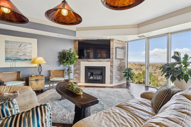 living room with a raised ceiling, a fireplace, wood finished floors, visible vents, and ornamental molding