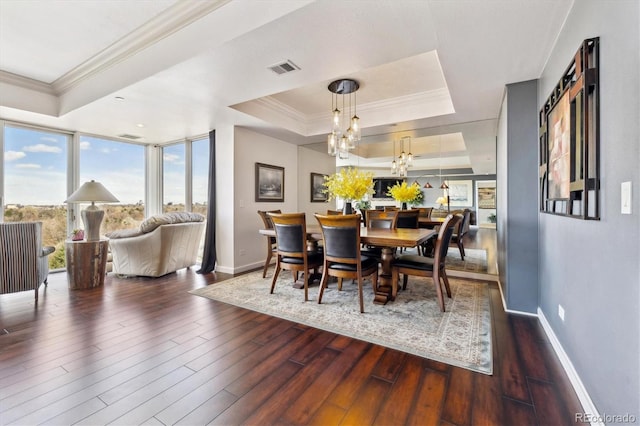 dining space featuring crown molding, a raised ceiling, baseboards, wood finished floors, and visible vents