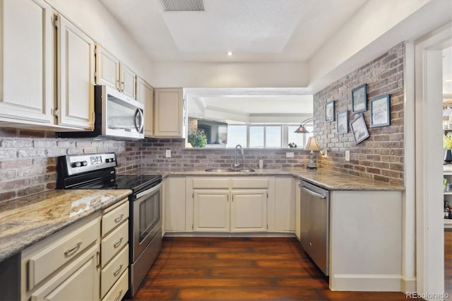 kitchen featuring dark wood-style flooring, tasteful backsplash, a sink, light stone counters, and stainless steel appliances
