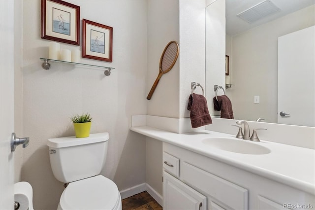 half bathroom featuring visible vents, baseboards, toilet, and vanity