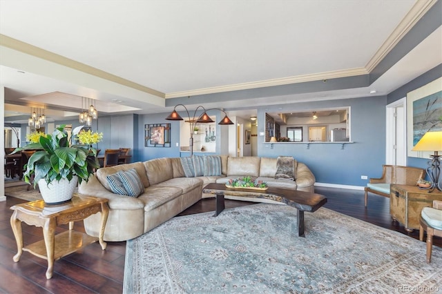 living area featuring a tray ceiling, an inviting chandelier, ornamental molding, and wood finished floors