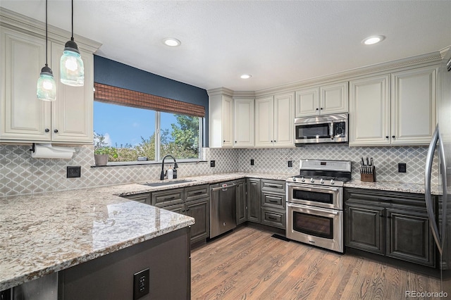 9924 Silver Maple Way, Highlands Ranch, CO 80129 - kitchen featuring appliances with stainless steel finishes, light stone countertops, light wood finished floors, tasteful backsplash, and hanging light fixtures