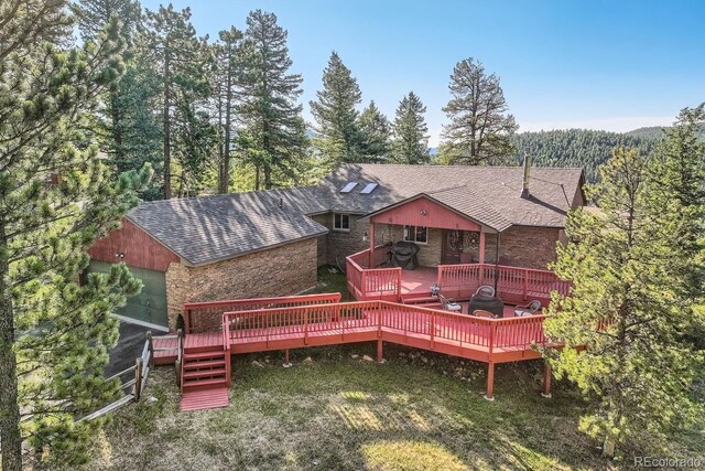 back of house with a garage, a yard, and a wooden deck