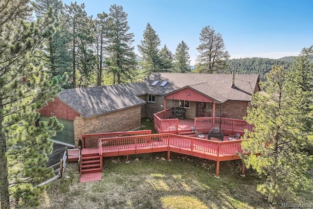 rear view of property with a wooden deck and a shingled roof