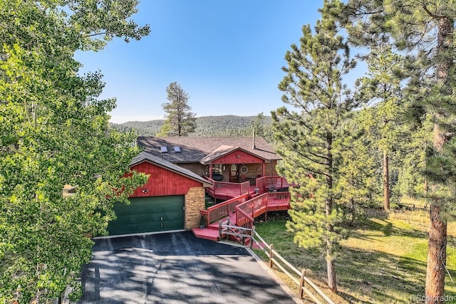 chalet / cabin with stairs, an attached garage, a deck, and driveway