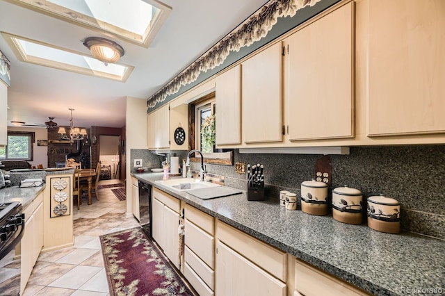 kitchen with black appliances, dark countertops, backsplash, cream cabinets, and a skylight