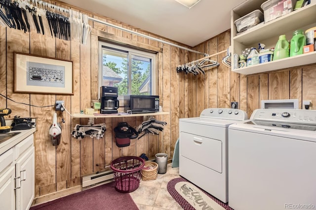 clothes washing area with laundry area, wooden walls, washing machine and dryer, and baseboard heating