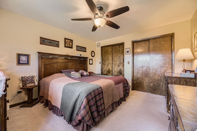 carpeted bedroom with two closets and ceiling fan