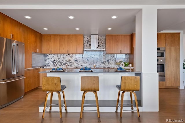 1020 15th St Unit 42A, Denver, CO 80202 - kitchen featuring stainless steel appliances, wall chimney exhaust hood, a breakfast bar, wood finished floors, and recessed lighting