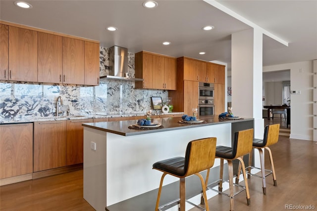 1020 15th St Unit 42A, Denver, CO 80202 - kitchen featuring wall chimney range hood, a sink, stainless steel double oven, light wood-style floors, and recessed lighting