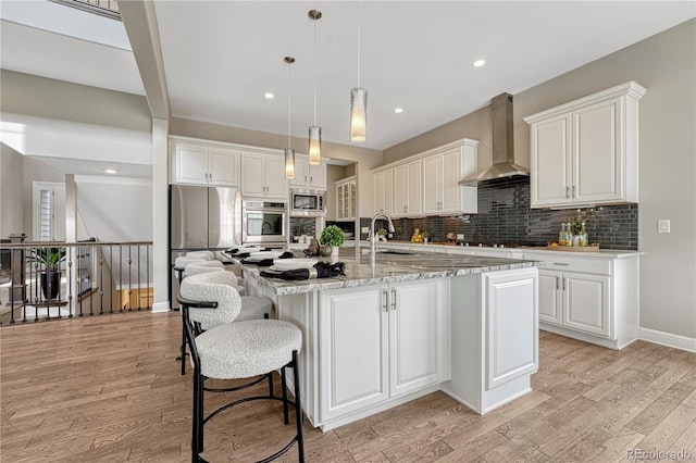 11821 Discovery Ln, Parker, CO 80138 - kitchen with wall chimney exhaust hood, appliances with stainless steel finishes, light wood-type flooring, tasteful backsplash, and white cabinets