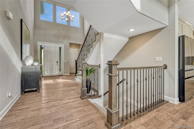 11821 Discovery Ln, Parker, CO 80138 - entryway with light wood-style flooring, a textured wall, a chandelier, a towering ceiling, and stairs