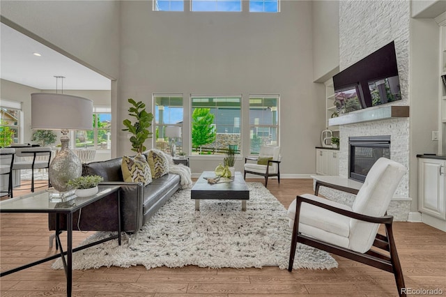 11821 Discovery Ln, Parker, CO 80138 - living area featuring wood finished floors, a stone fireplace, a high ceiling, and recessed lighting