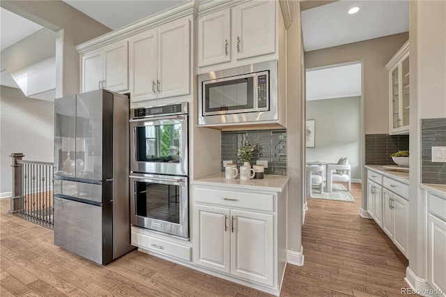 11821 Discovery Ln, Parker, CO 80138 - kitchen with stainless steel appliances, light wood finished floors, light countertops, decorative backsplash, and recessed lighting