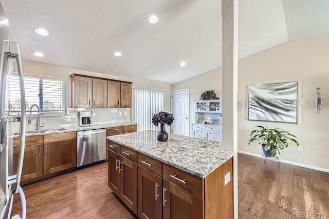 kitchen featuring sink, dishwasher, a kitchen island, dark hardwood / wood-style flooring, and vaulted ceiling