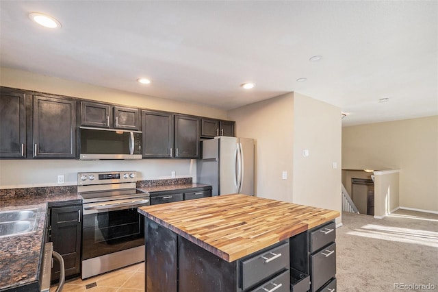 kitchen featuring wood counters, dark brown cabinetry, a center island, light colored carpet, and stainless steel appliances