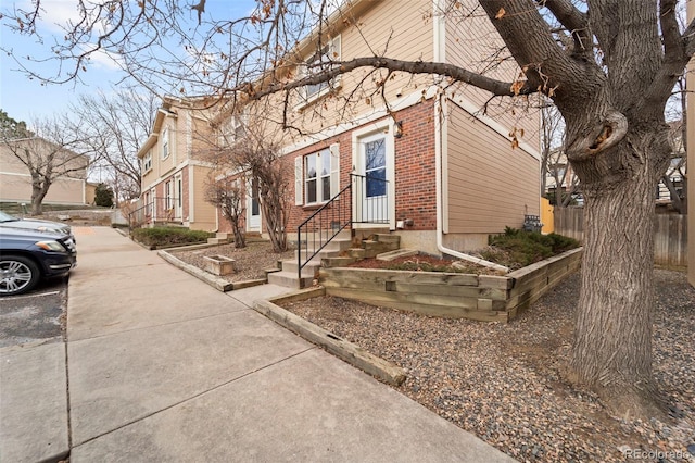 view of front of home featuring brick siding and fence