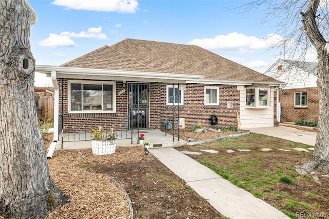 bungalow-style house featuring a shingled roof, fence, and brick siding