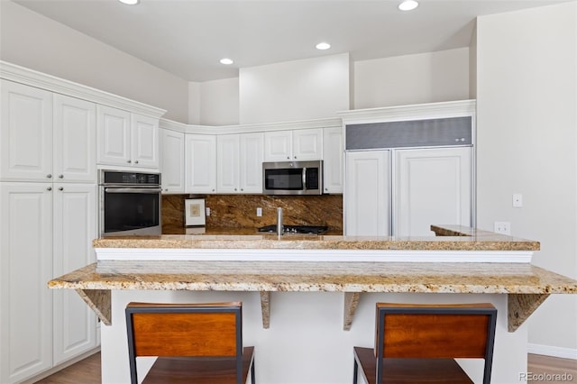 301 Garfield St Unit 1E, Denver, CO 80206 - kitchen featuring stainless steel appliances, a kitchen bar, white cabinets, and recessed lighting