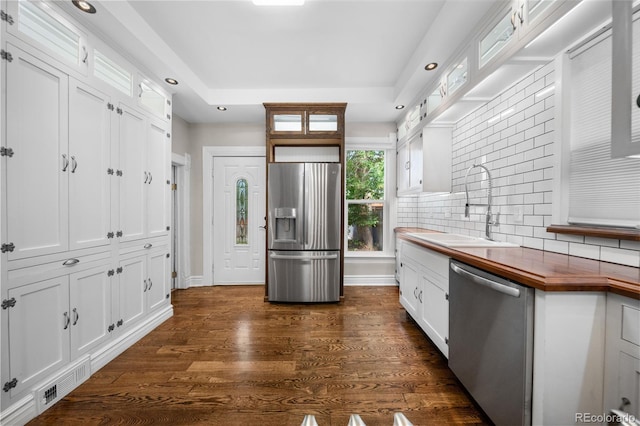 3254 Newton St, Denver, CO 80211 - kitchen featuring appliances with stainless steel finishes, white cabinetry, a tray ceiling, decorative backsplash, and recessed lighting