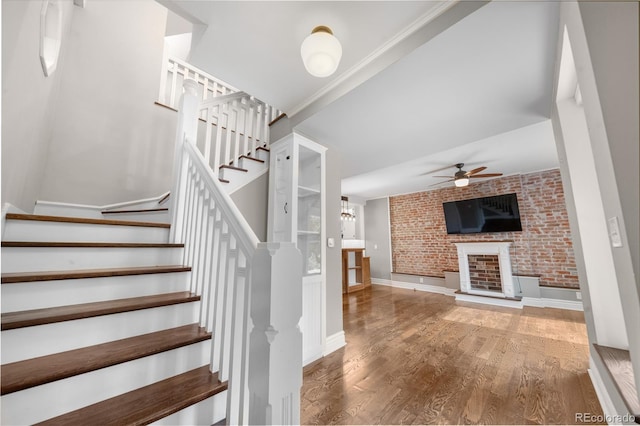 3254 Newton St, Denver, CO 80211 - stairway featuring a ceiling fan, wood finished floors, brick wall, and a brick fireplace