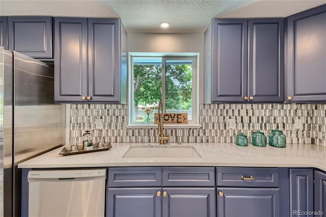 kitchen with sink, light stone countertops, a textured ceiling, appliances with stainless steel finishes, and tasteful backsplash