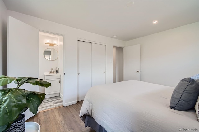 bedroom featuring connected bathroom, a closet, sink, and light hardwood / wood-style floors