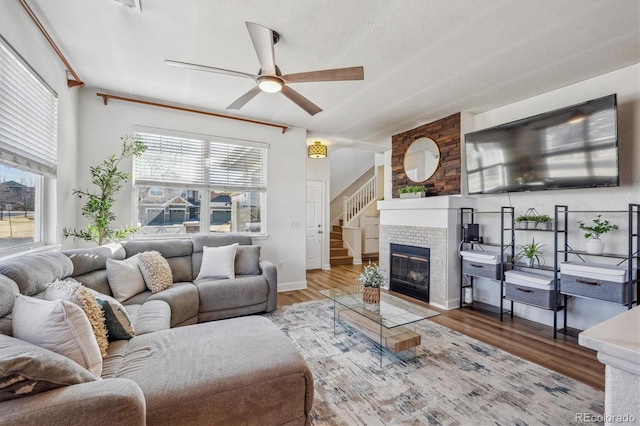 living room with stairway, wood finished floors, a textured ceiling, and ceiling fan