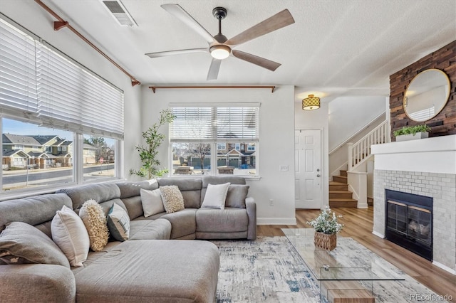 living area featuring a textured ceiling, visible vents, light wood finished floors, and ceiling fan