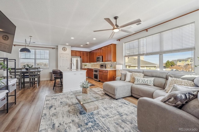 living area featuring light wood-type flooring, visible vents, recessed lighting, baseboards, and ceiling fan