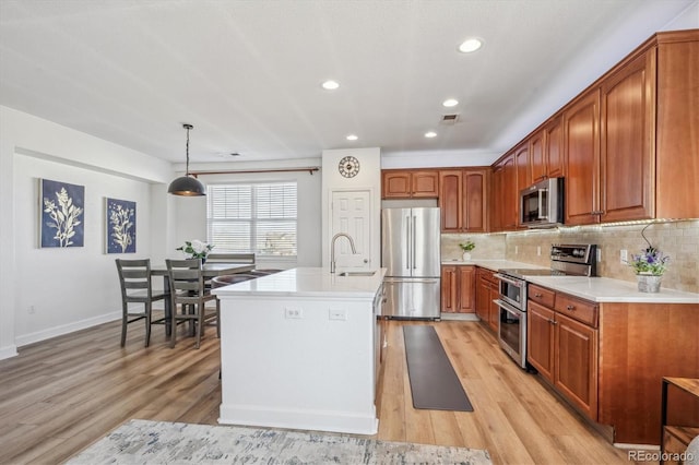 kitchen with tasteful backsplash, appliances with stainless steel finishes, light wood-type flooring, and a sink