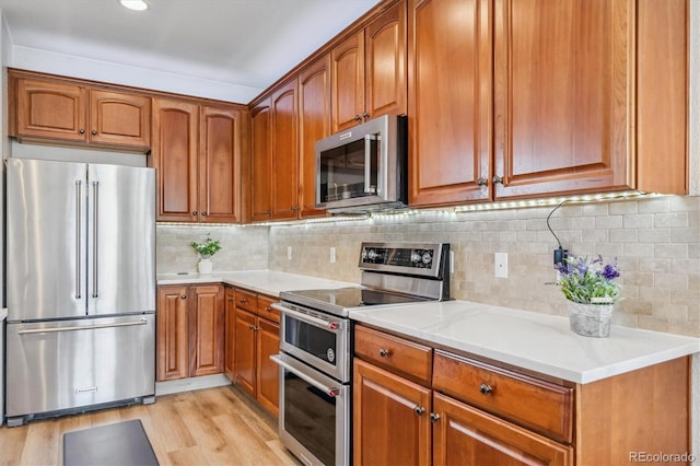 kitchen featuring light wood finished floors, brown cabinets, stainless steel appliances, and light countertops