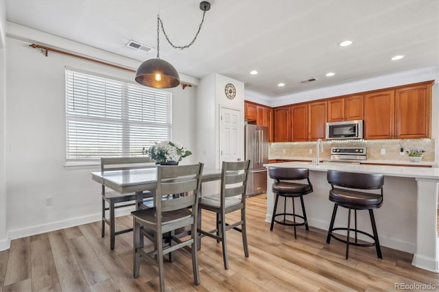 kitchen featuring visible vents, stainless steel appliances, light countertops, light wood-style floors, and tasteful backsplash