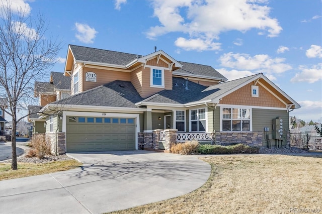 craftsman inspired home with a front yard, roof with shingles, concrete driveway, a garage, and stone siding