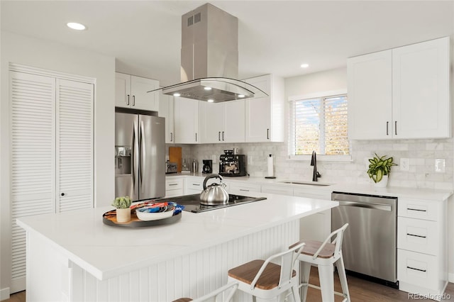 6163 W 76th Ave, Arvada, CO 80003 - kitchen featuring appliances with stainless steel finishes, island exhaust hood, tasteful backsplash, white cabinets, and a center island