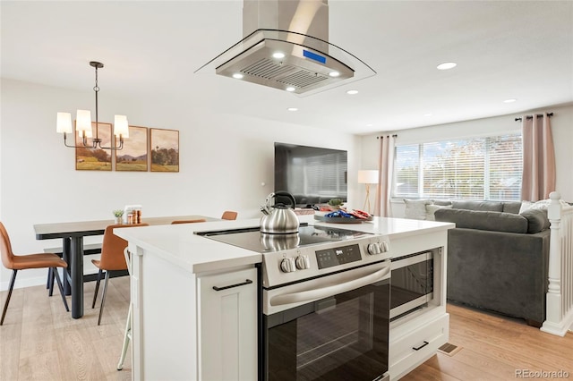 6163 W 76th Ave, Arvada, CO 80003 - kitchen featuring stainless steel appliances, open floor plan, island range hood, a chandelier, and light wood-style floors