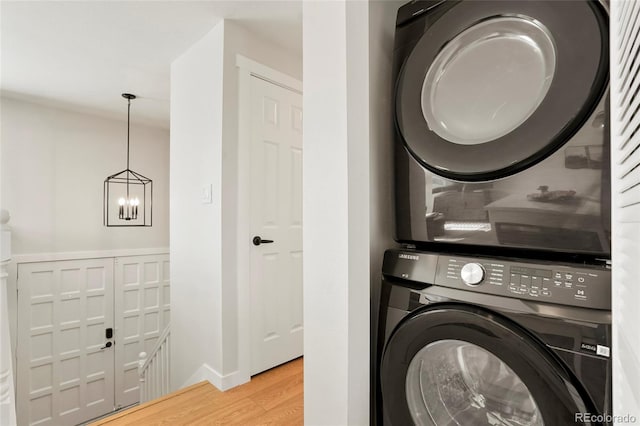 6163 W 76th Ave, Arvada, CO 80003 - laundry room with stacked washing machine and dryer, light wood finished floors, and a chandelier