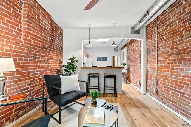 living room featuring brick wall and light wood-type flooring