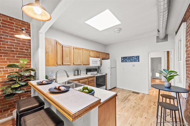 kitchen with brick wall, light hardwood / wood-style floors, white appliances, and a skylight