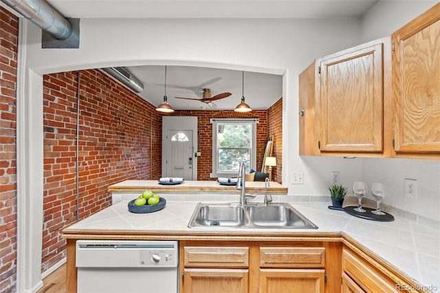 kitchen featuring white dishwasher, brick wall, sink, decorative light fixtures, and light brown cabinetry