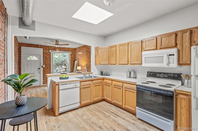 kitchen with white appliances, sink, light hardwood / wood-style floors, ceiling fan, and brick wall