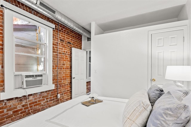 bedroom with brick wall and cooling unit