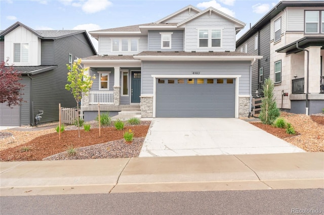 8582 Cheraw St, Littleton, CO 80125 - craftsman inspired home with covered porch, an attached garage, stone siding, and driveway