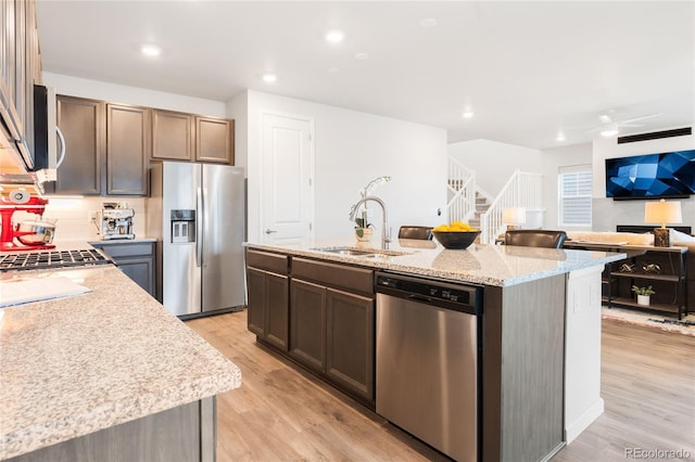 8582 Cheraw St, Littleton, CO 80125 - kitchen with stainless steel appliances, light wood-type flooring, a kitchen island with sink, light stone countertops, and open floor plan