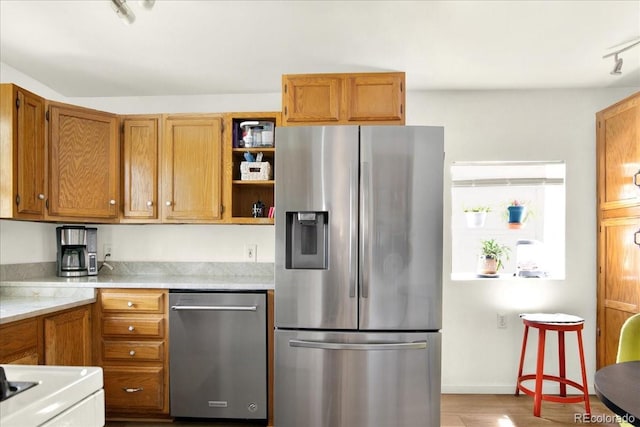 5211 Dover St, Arvada, CO 80002 - kitchen featuring appliances with stainless steel finishes, light countertops, brown cabinetry, open shelves, and light wood-style flooring