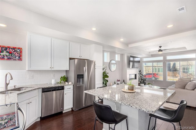 kitchen featuring a kitchen bar, stainless steel appliances, ceiling fan, and sink