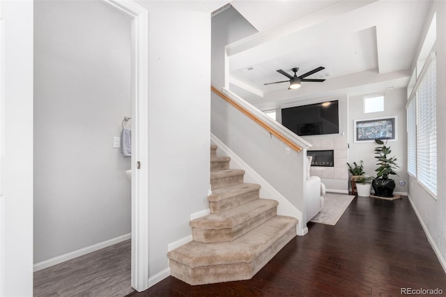 foyer entrance with a tile fireplace, dark hardwood / wood-style floors, and ceiling fan