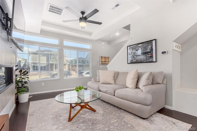 living room featuring hardwood / wood-style floors, ceiling fan, and a tray ceiling